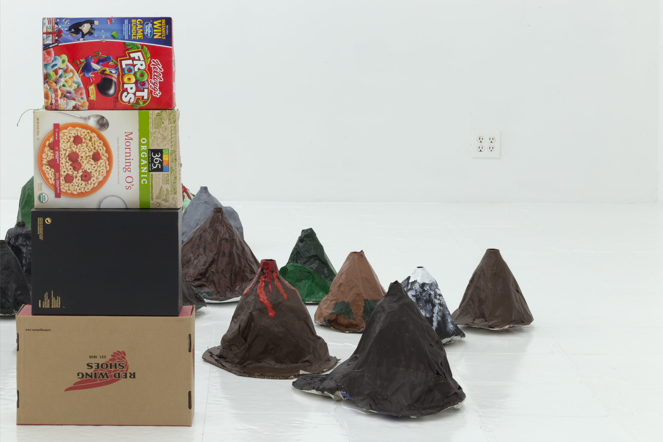 Stack of cereal and shoe boxes in the foreground; papier mache volcanoes in the background