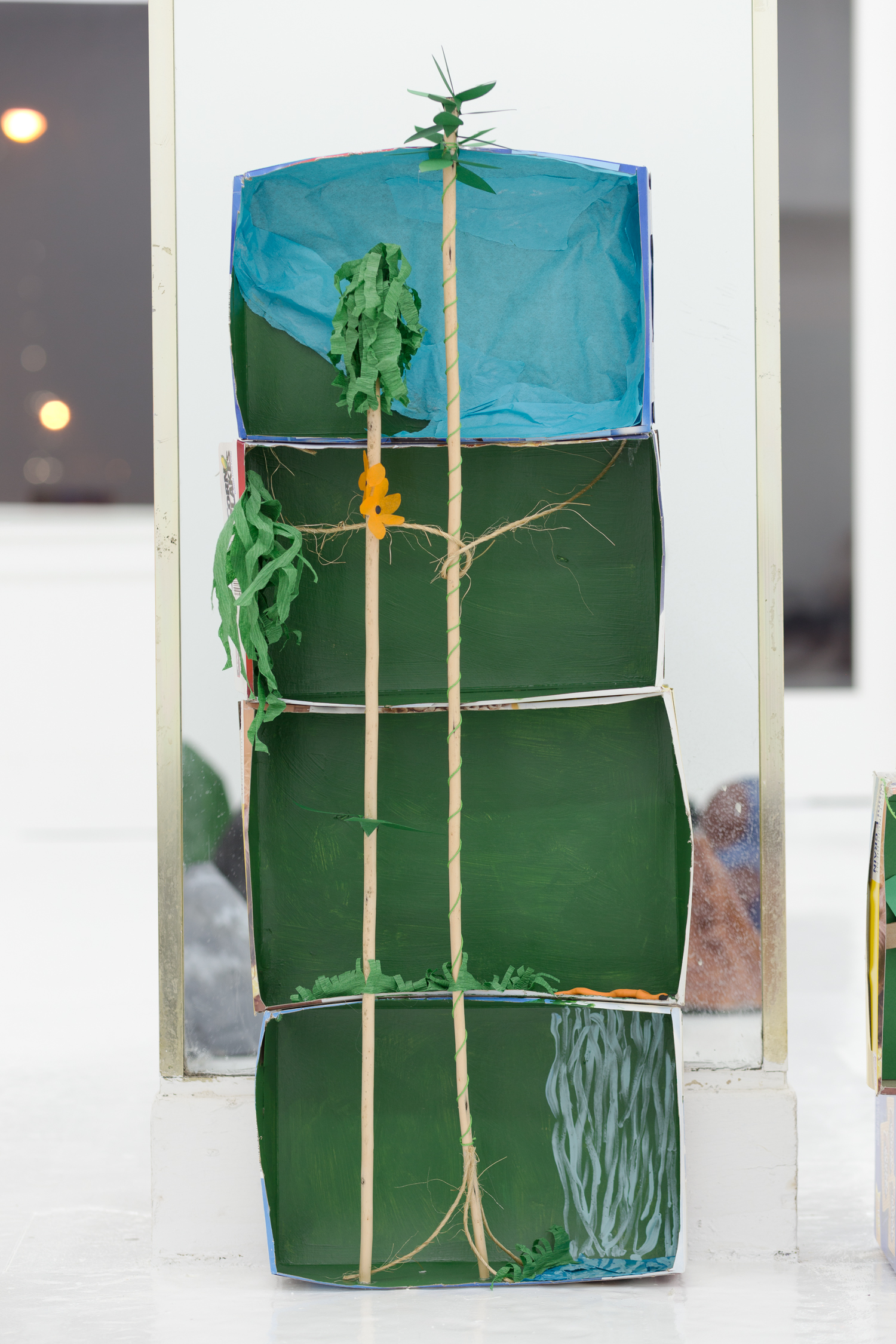 Rainforest diorama made of stacked boxes, wooden dowels, and crepe paper