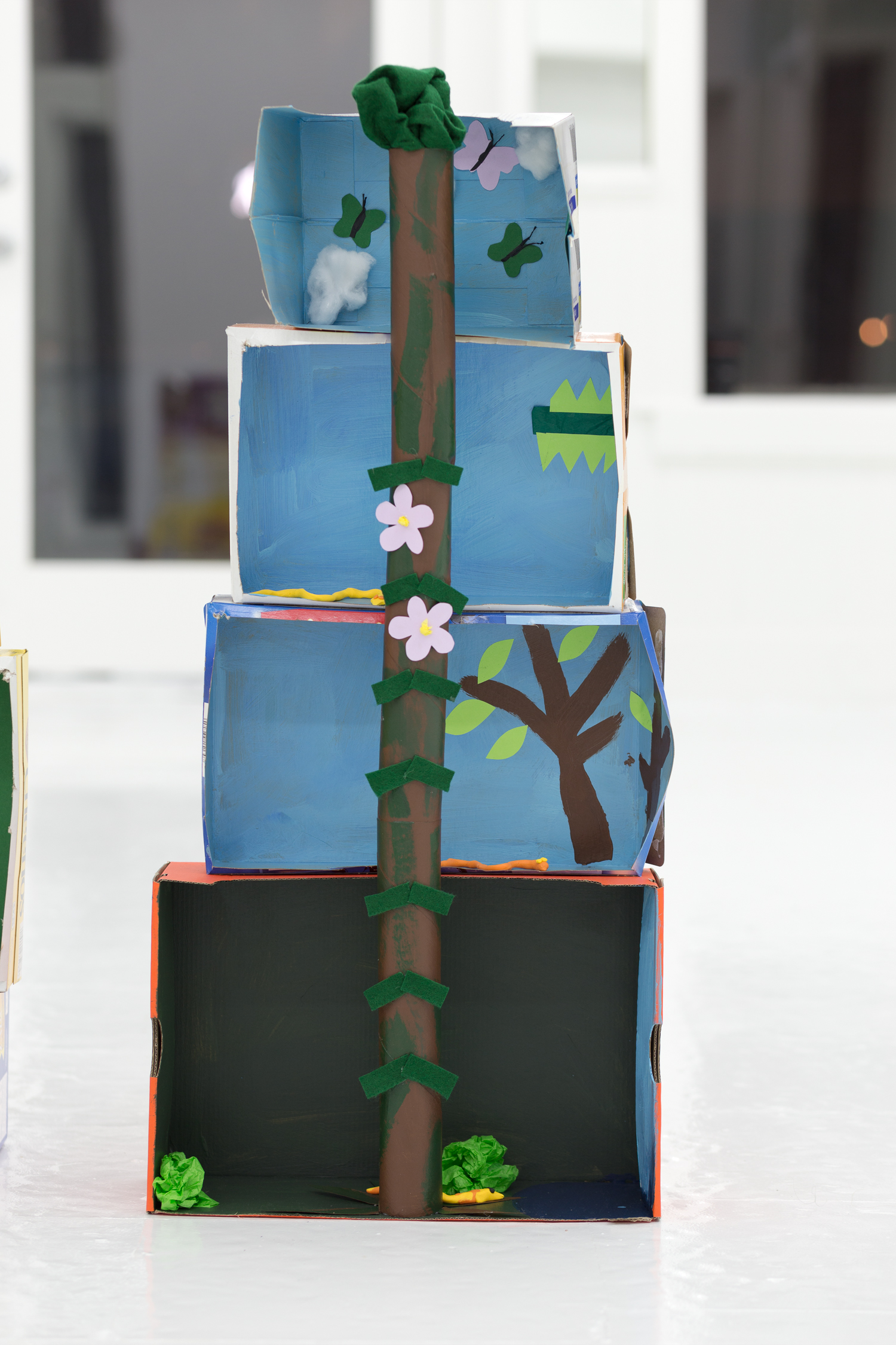 Rainforest diorama made of stacked boxes, toilet paper tubes, and crepe paper