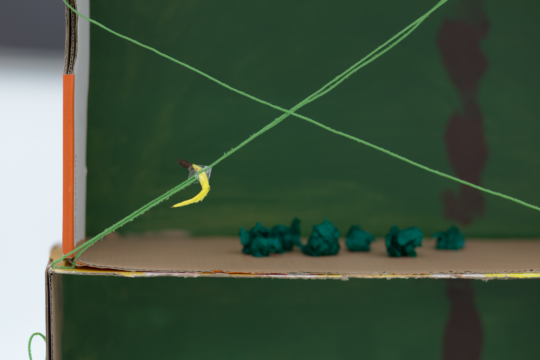 Close up of a tiny crepe paper banana suspended on a string