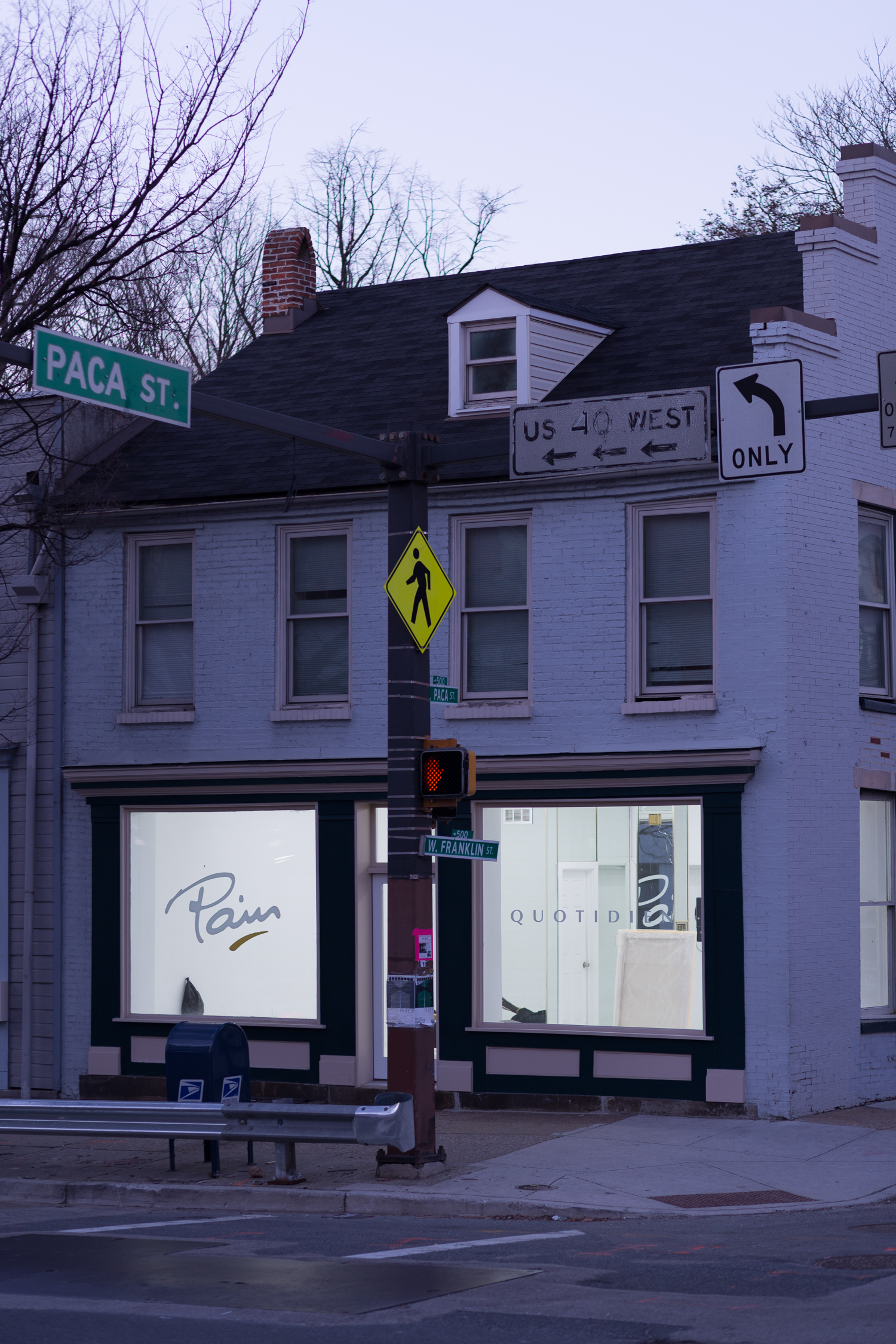 The gallery as seen from across the street at dusk, with ‘Pain Quotidien’ decals in the front windows