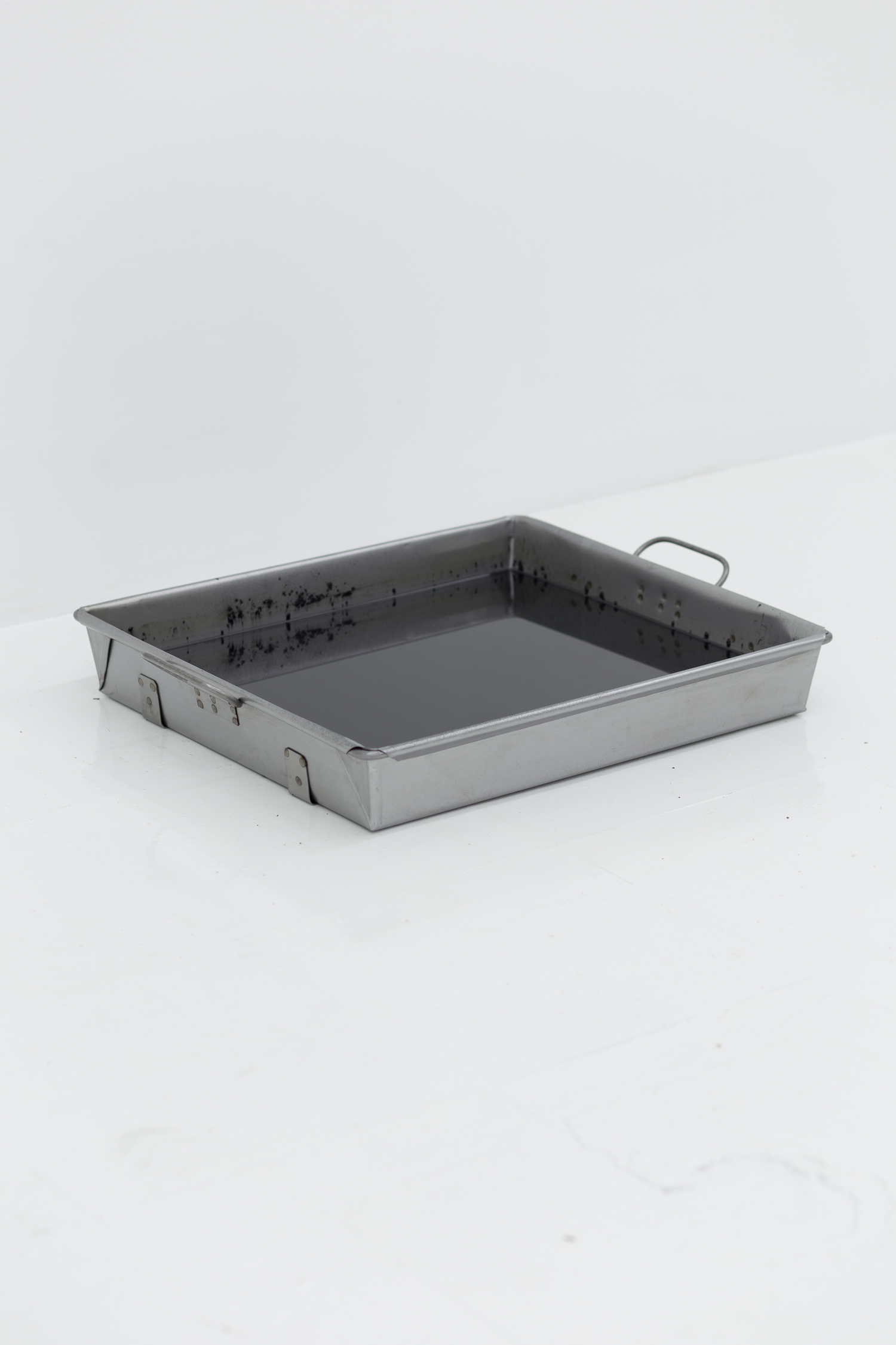 A metal pan of printer toner and motor oil sits on the floor