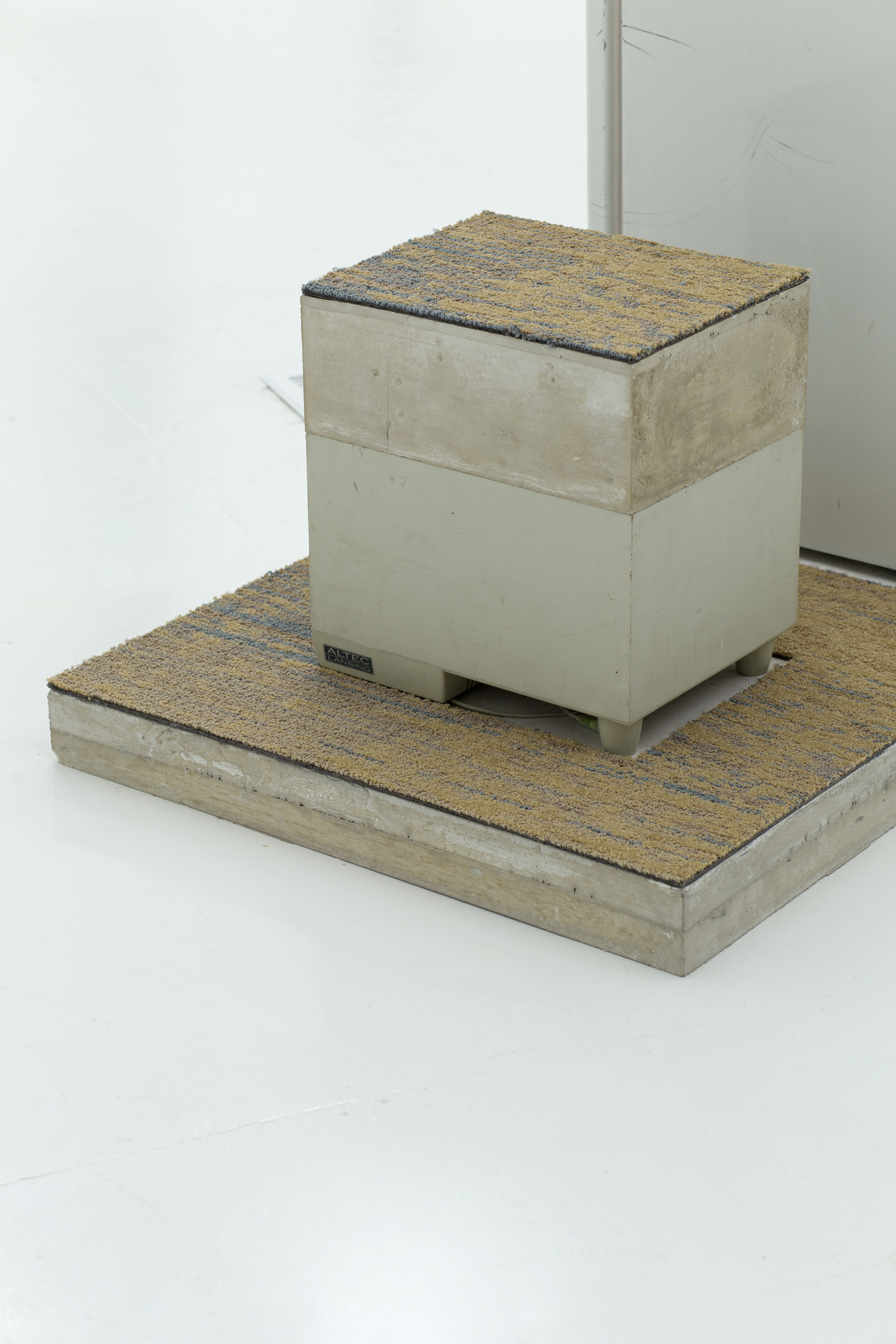 A plastic appliance is topped with concrete and low-pile carpet