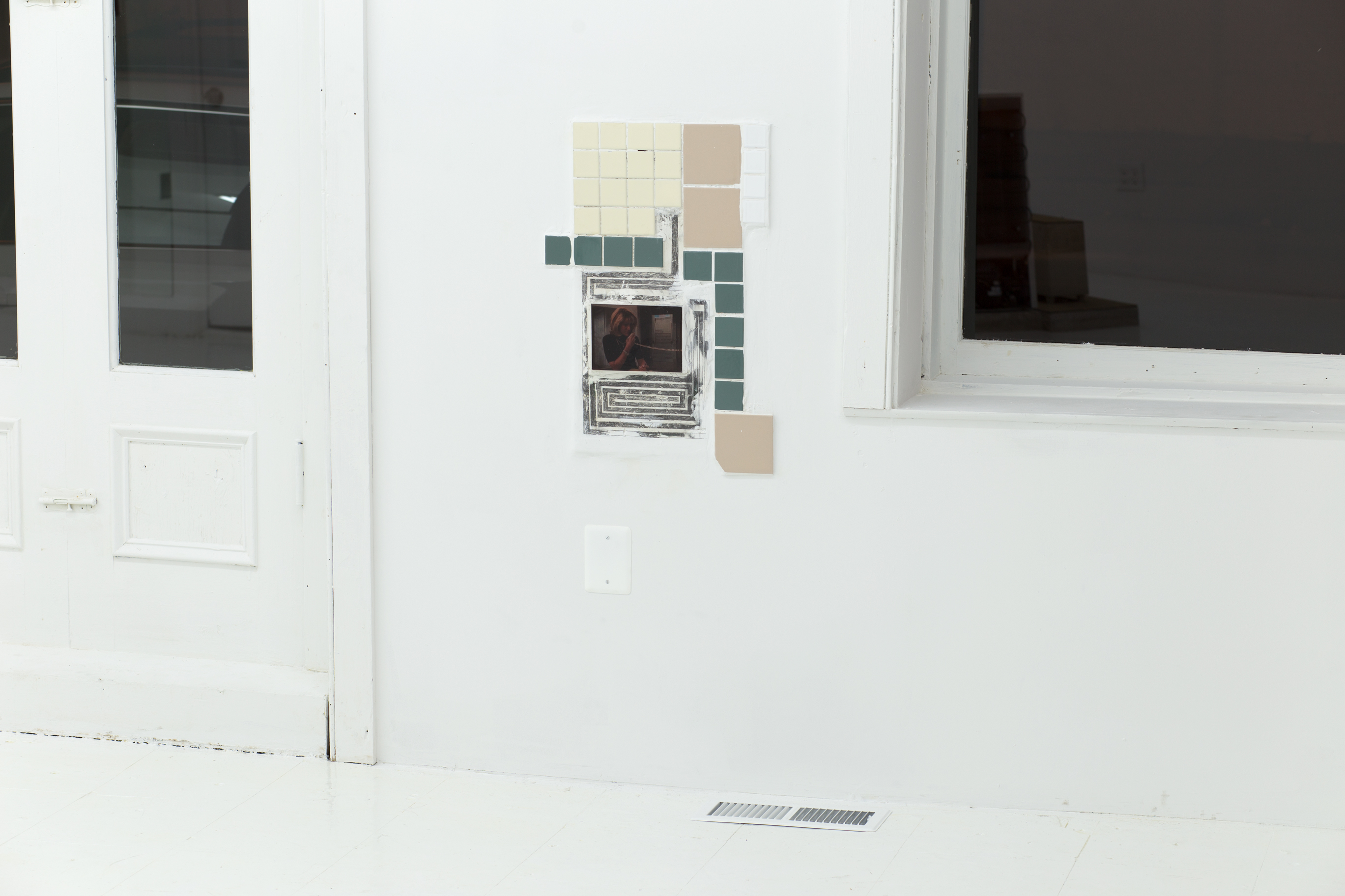 A tile collage is set directly into the drywall between windows