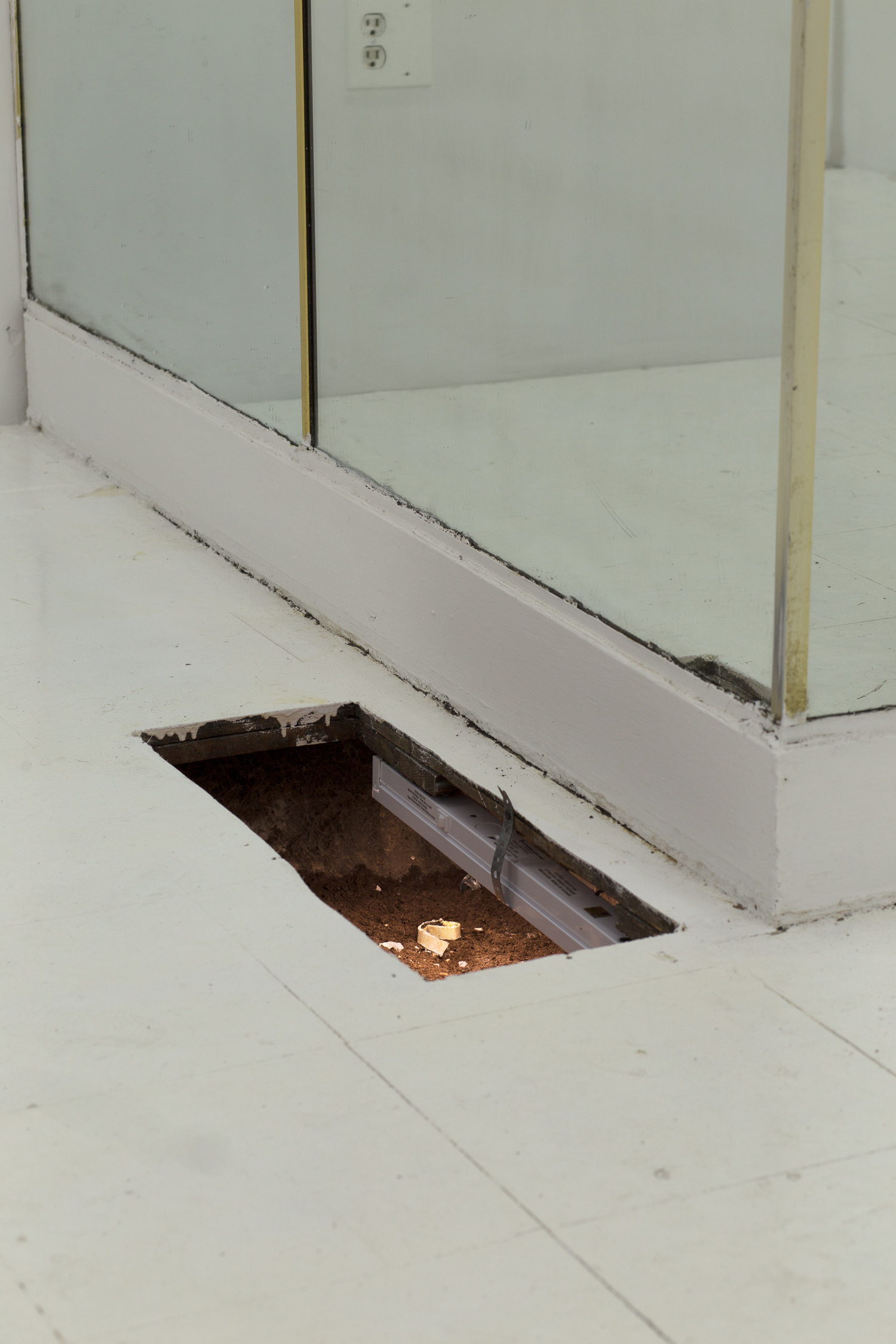 A hole in the floor is illuminated by a long fluorescent