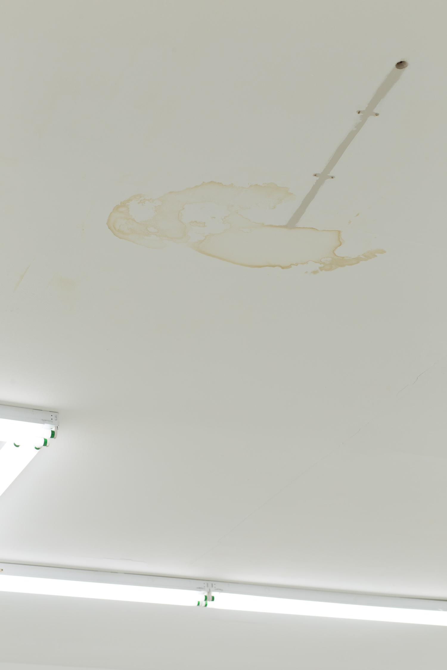 There is a brown water stain on the ceiling and the suggestion of a removed pipe.