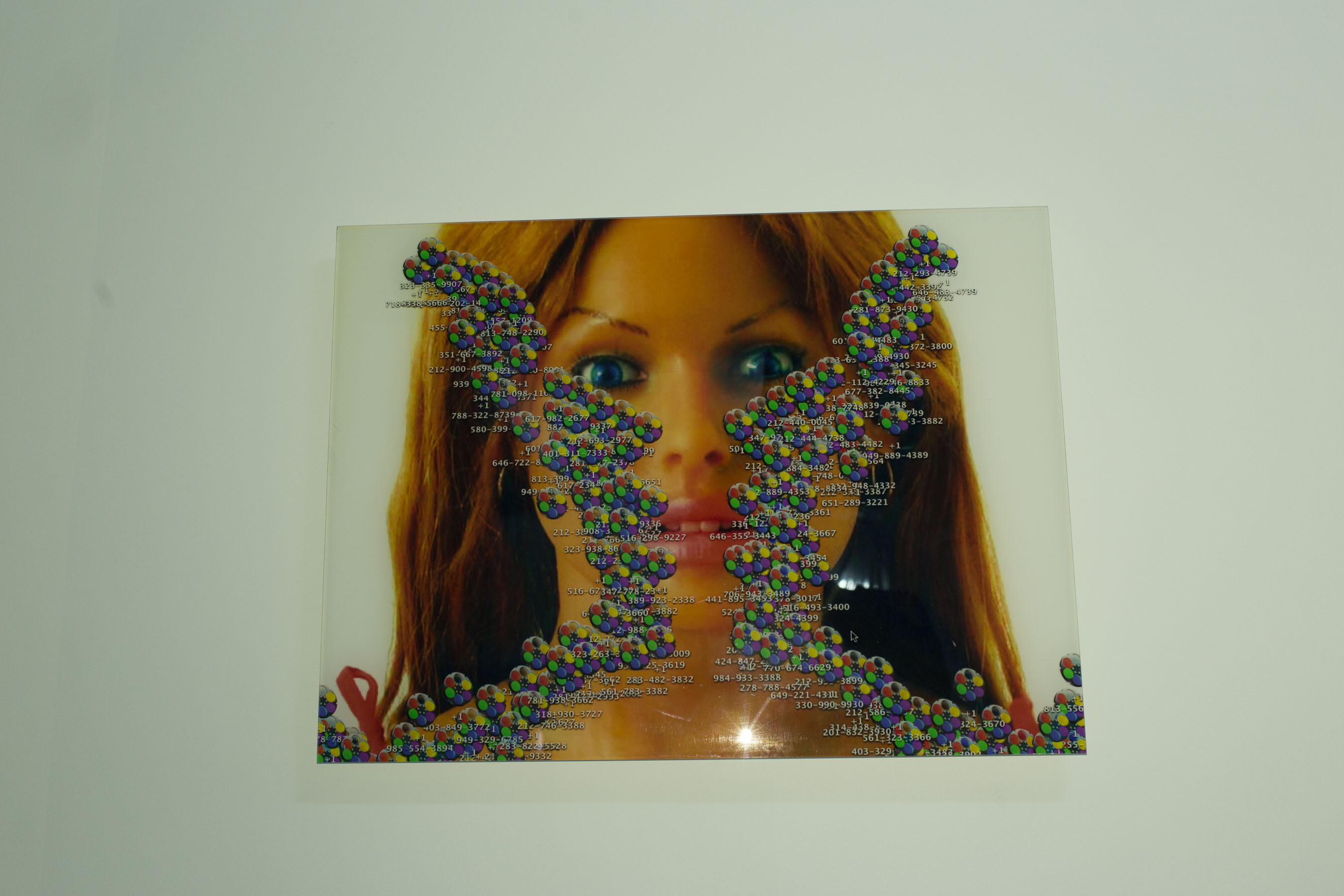 A wall work by Jessie Stead: a print of a real doll face covered partially by files, as if on a desktop background