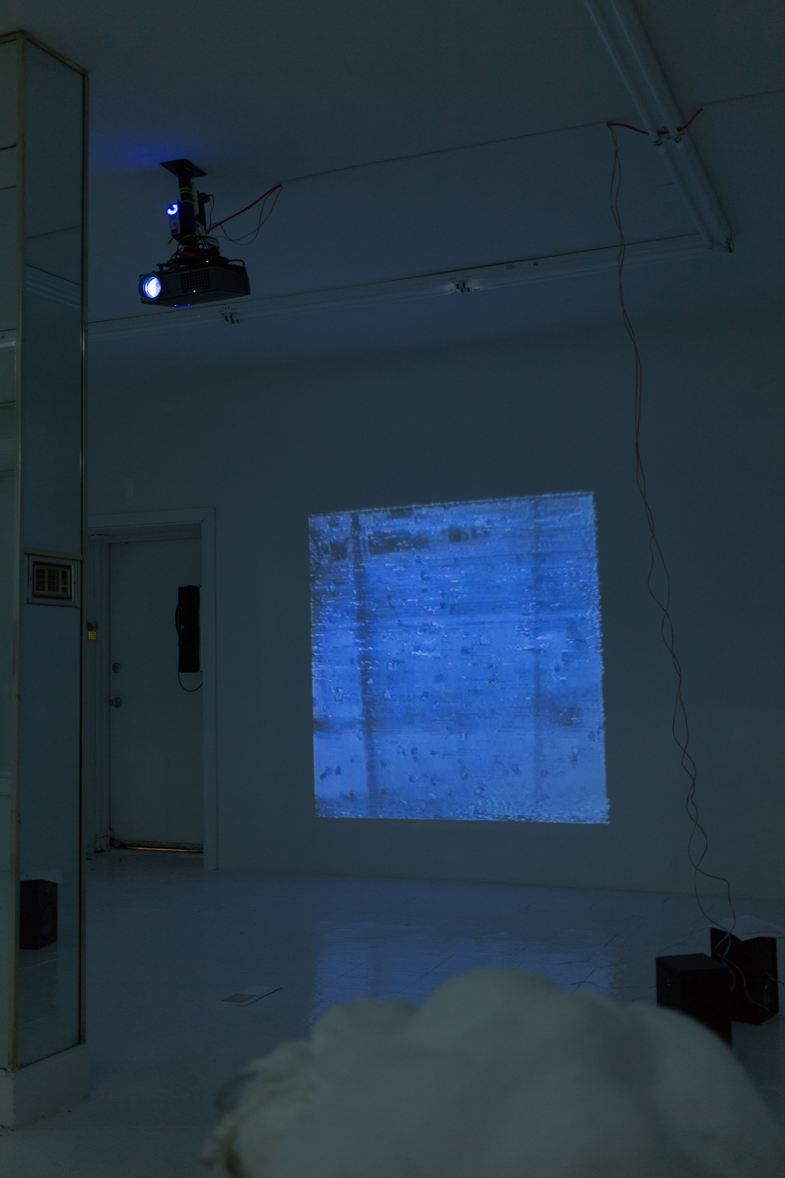 The projector is pointed and the mirror, so the projection, a video by Orphan Drift, is reflected back onto the wall behind