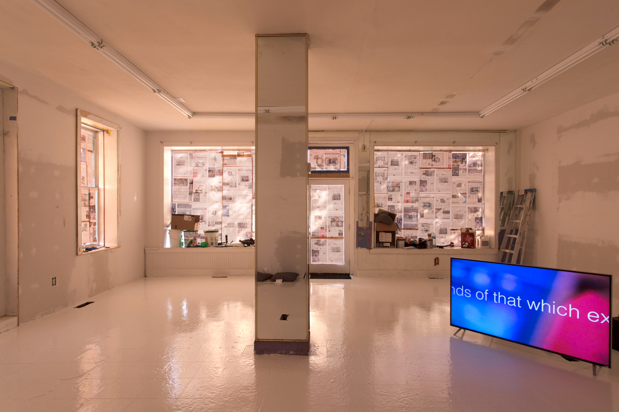 Facing toward the door, pink light filters through the windows and words float across the screen