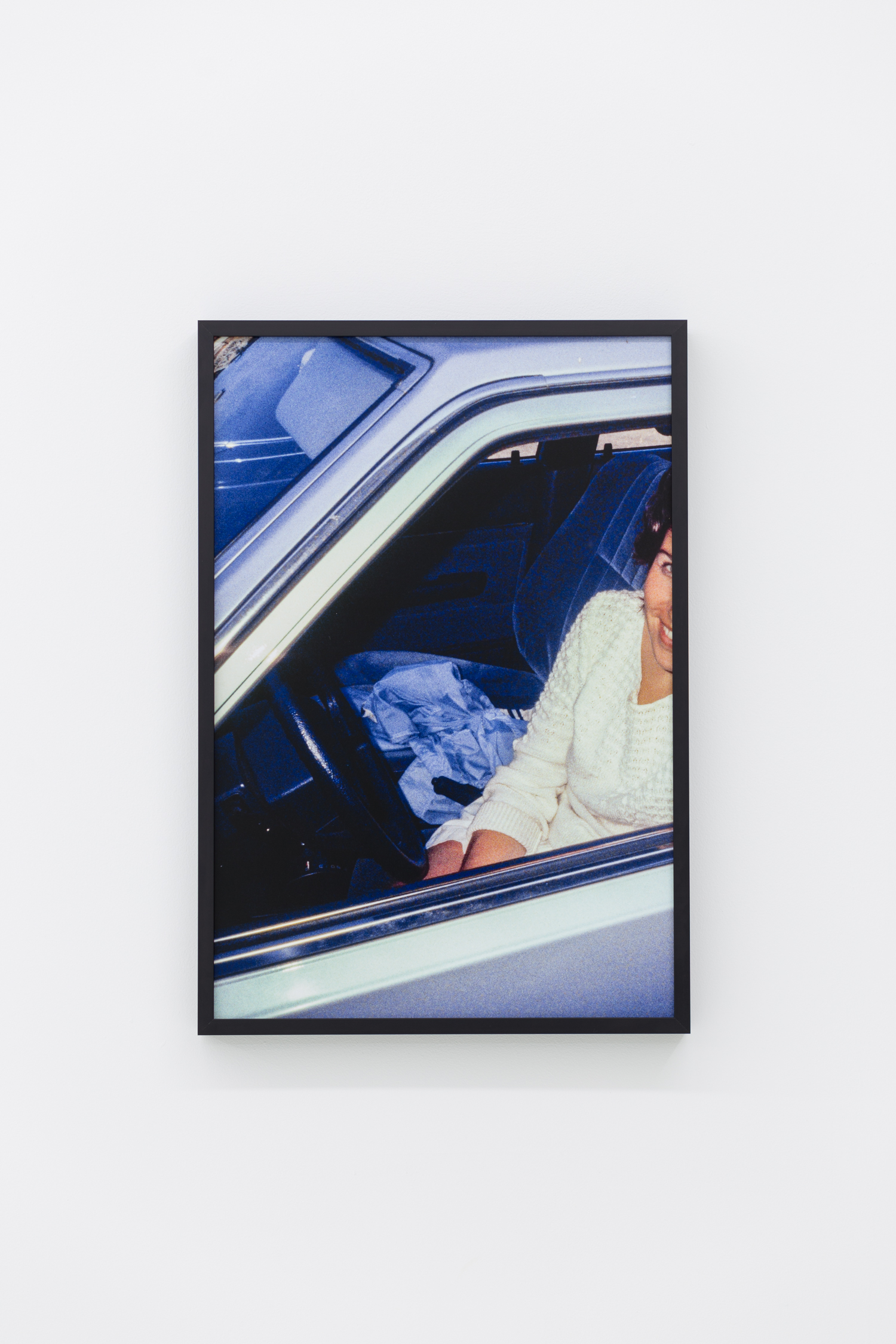 Photo of a woman in white sitting in the driver’s seat of a car