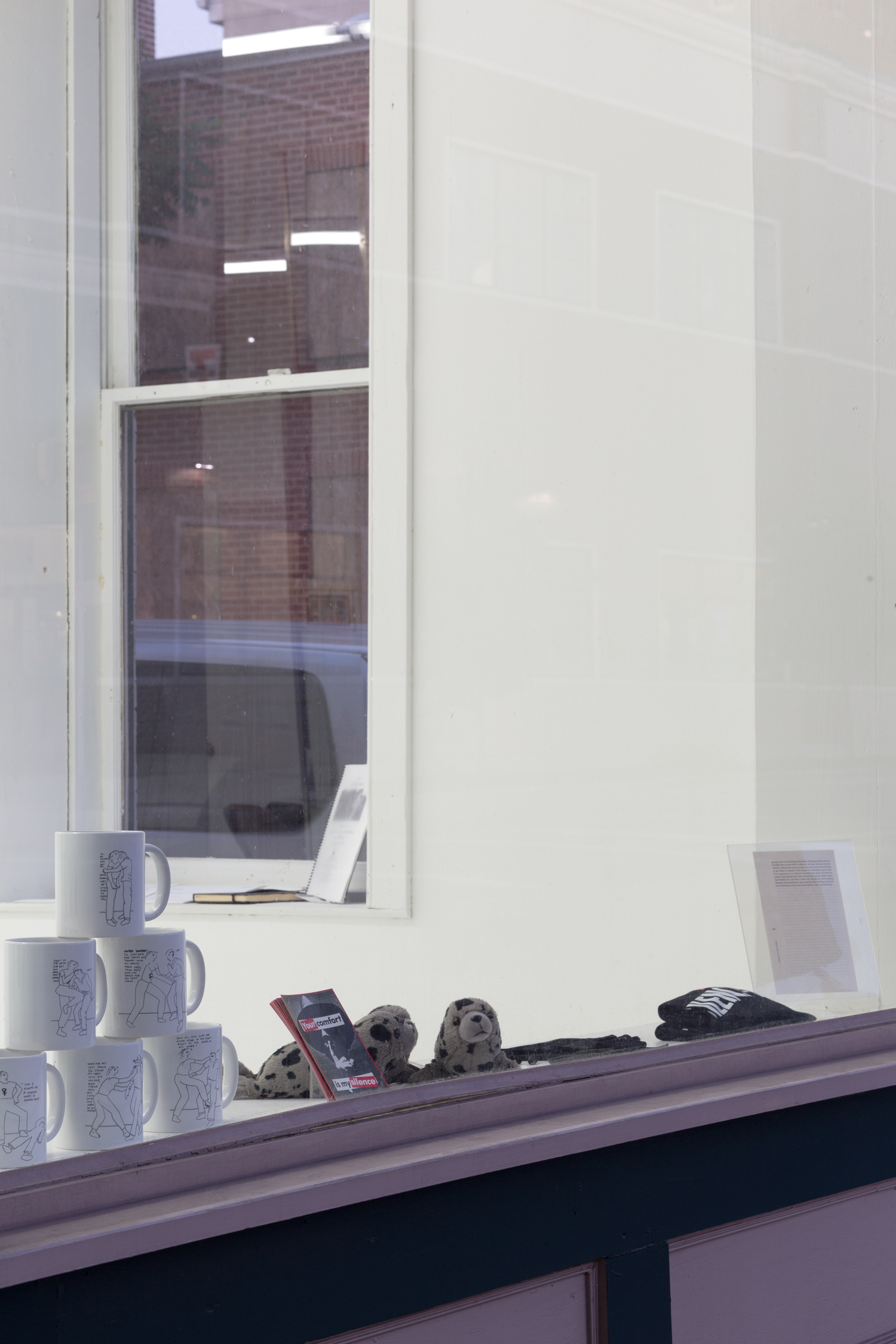 Items sit on the windowsill: a stack of mugs, pamphlets, and seal stuffed animals