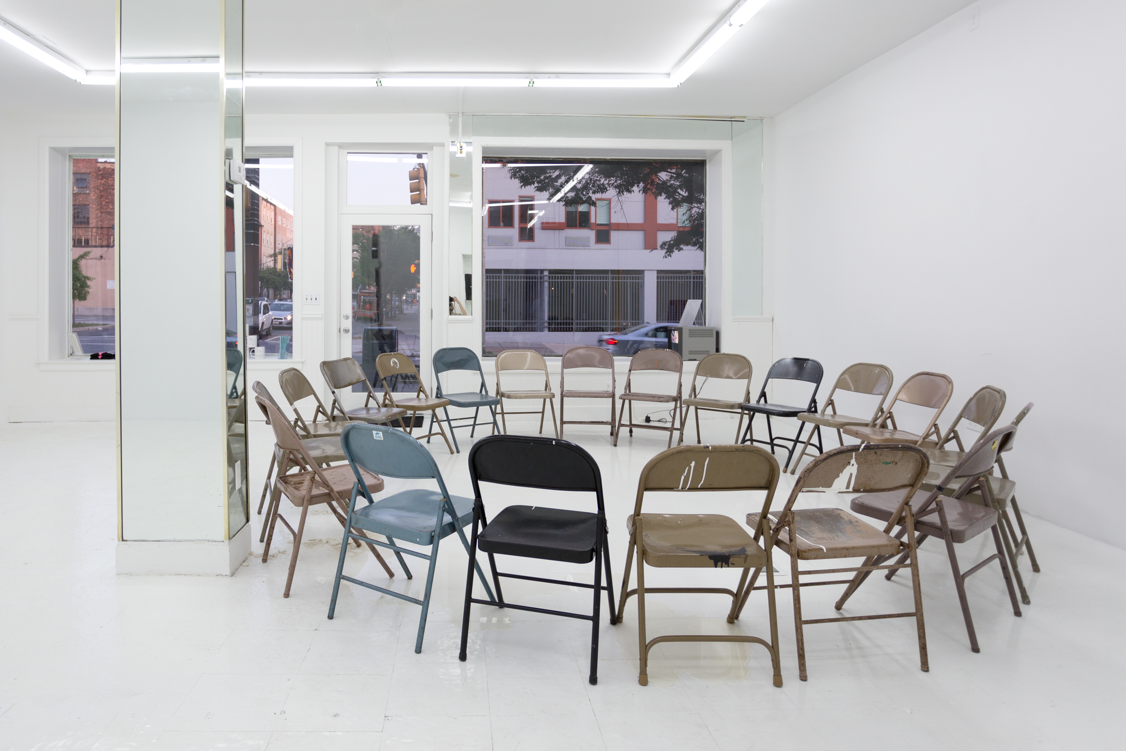 There is a circle of folding chairs in the gallery