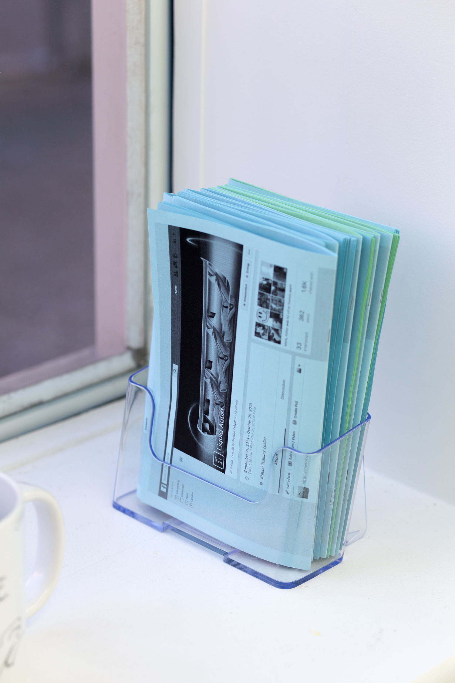 A stack of zines sits inside a plastic stand