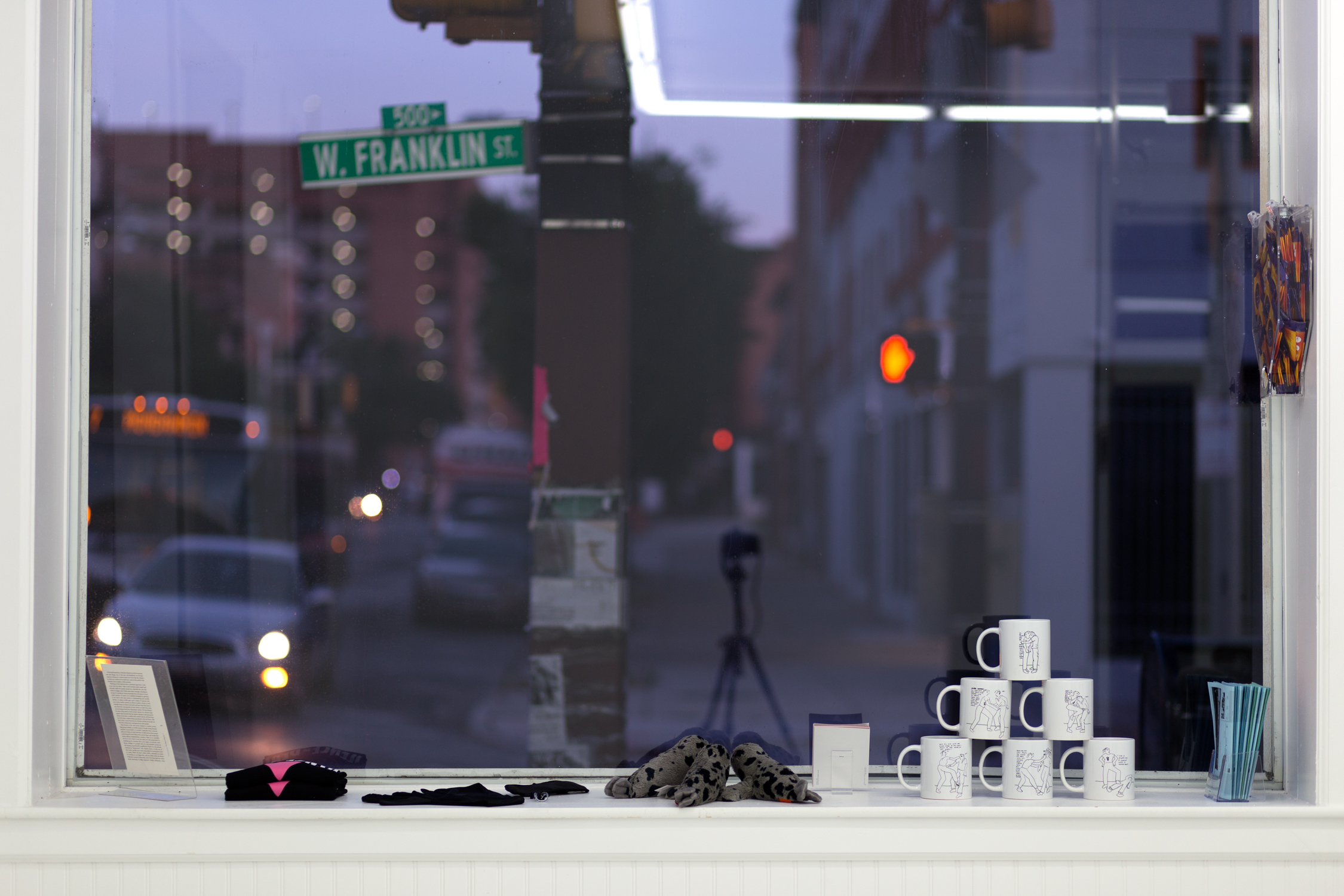 Items sit on the windowsill: a stack of mugs, pamphlets, and seal stuffed animals